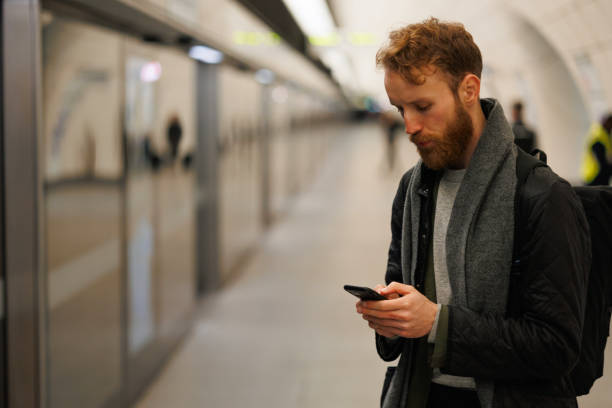 istock Man using smartphone on the platform of the subway station while waiting for the train 1472478391