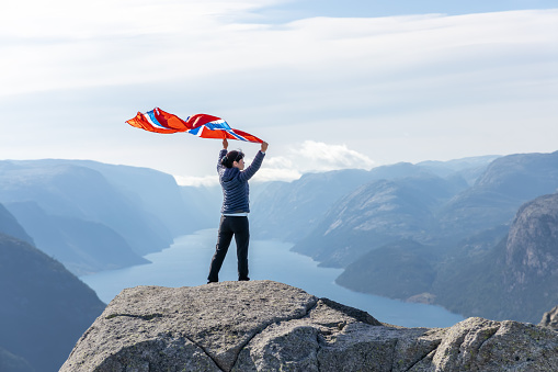 Woman with a waving flag of Norway on the background of nature