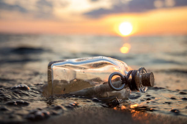 Message in the bottle against the Sun setting down stock photo