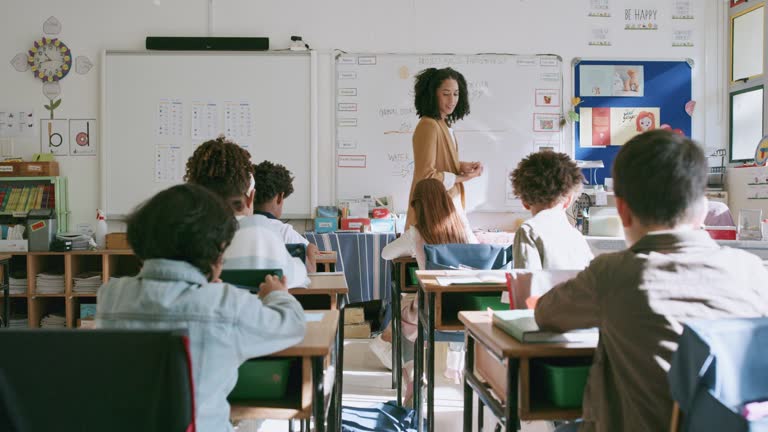 Classroom, education and teaching to learn, teacher walking and giving lesson with students and scholarship. Science class, black woman and young children in elementary school, help and learning