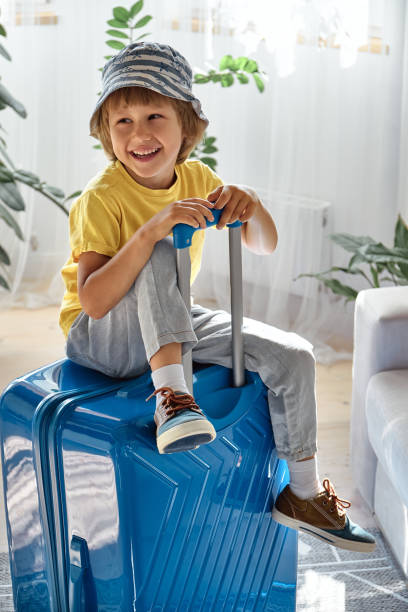 istock A child sitting on a suitcase have fun and laughs, waiting for a trip on vacation 1472482712