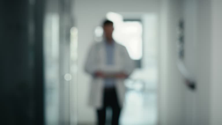 Blurred video of medical staff walking across the hospital corridor. Shot with RED helium camera in 8K.