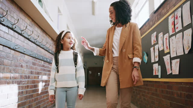 School, education and student walking with teacher in hallway or corridor for conversation. Learning, scholarship and support, care of woman or educator with kid or girl in kindergarten for studying.