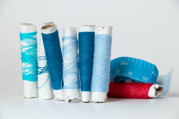 Blue threads and red in different shades on a spool and centimeter tape on a white isolated background, fashion