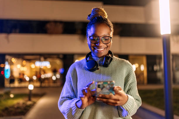 istock Young smiling casually clothed woman using phone outdoors 1472499562