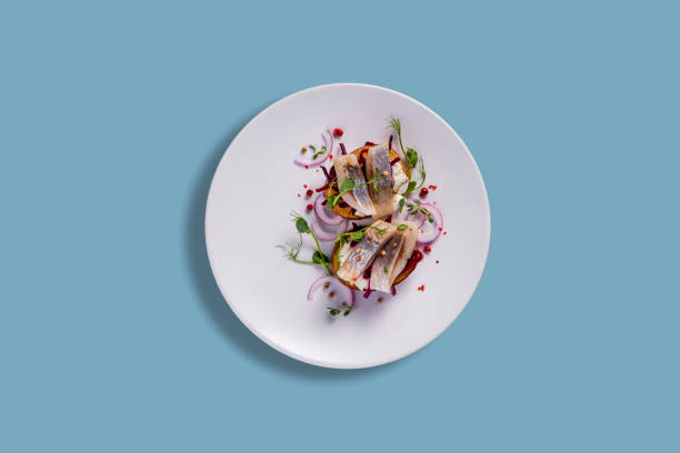 istock Sandwiches with herring, pea sprouts, onions, peppercorns and caviar paste in a plate on a blue background 1472500874