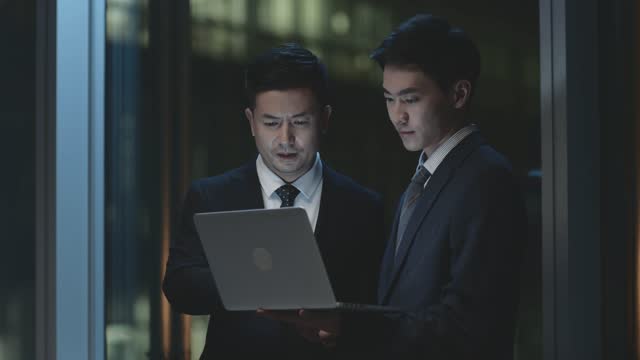 asian corporate executives discussing business in office at night