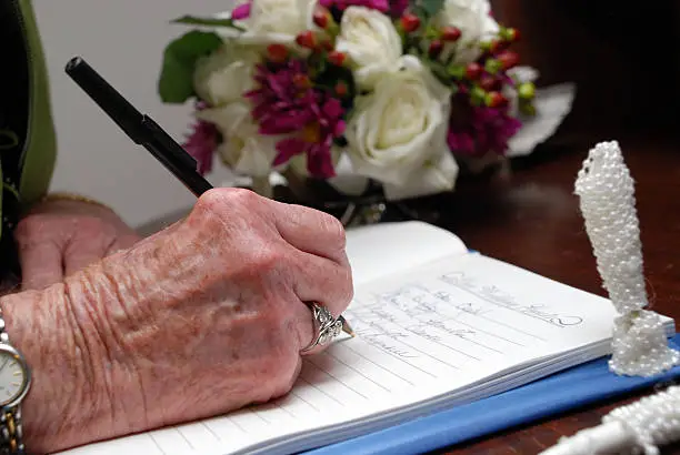 hand of an old lady signing a guestbook
