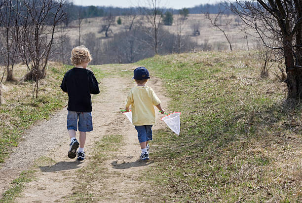 Two kids walking along nature path stock photo