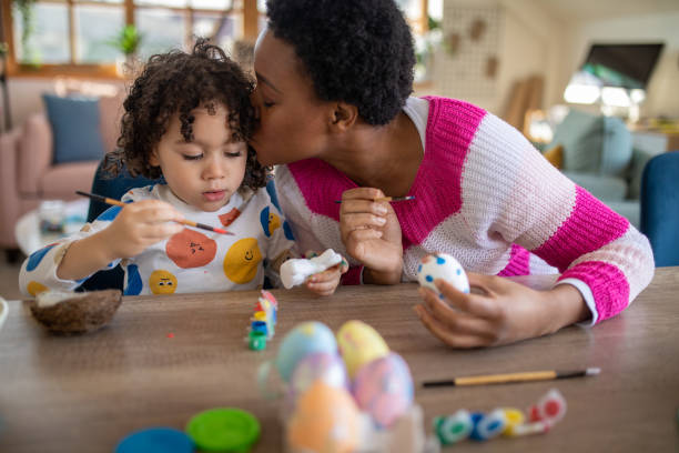 istock African mother and her multiracial son coloring Easter eggs at home 1472504954