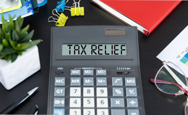 istock Calculator with the text TAX RELIEF on the screen and office tools on background. High quality photo 1472506317