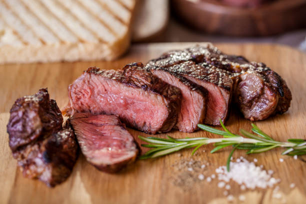 gegrillte schweinesteakstücke mit einem zweig rosmarin, pfeffer und salz, gebratene brotstücke auf einem holzbrett. horizontale ausrichtung - steak filet mignon beef fillet steak stock-fotos und bilder