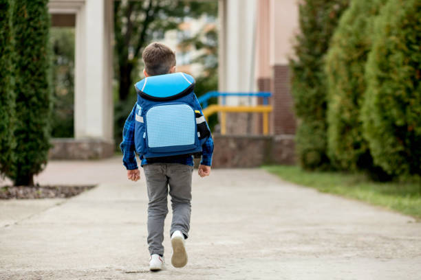 istock Little first grader with a blue backpack goes to school 1472509004