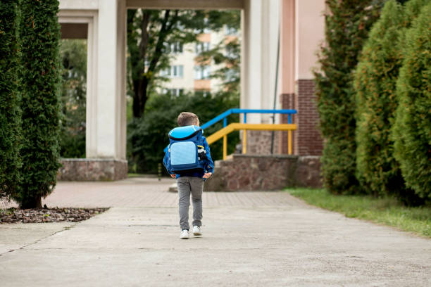 istock Little first grader with a blue backpack goes to school 1472509021