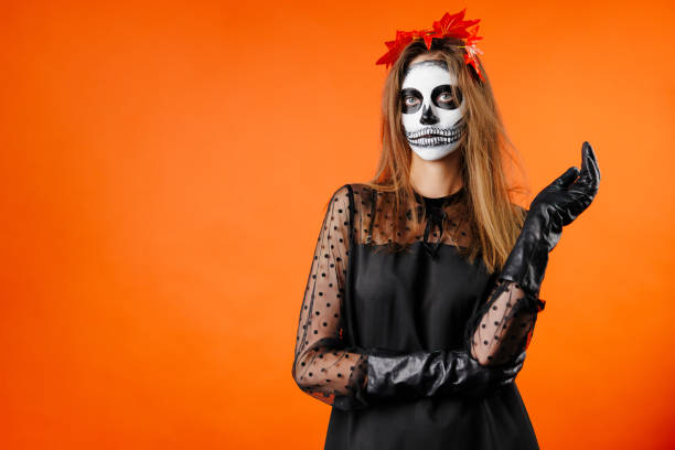 istock Beautiful woman dressed as witch for Halloween on orange background with space for text 1472509248
