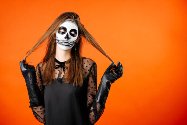 Scary female face with helloween horror grimm. Orange background. Scary female face with helloween horror grimm. Orange background. High quality photo grimma stock pictures, royalty-free photos & images