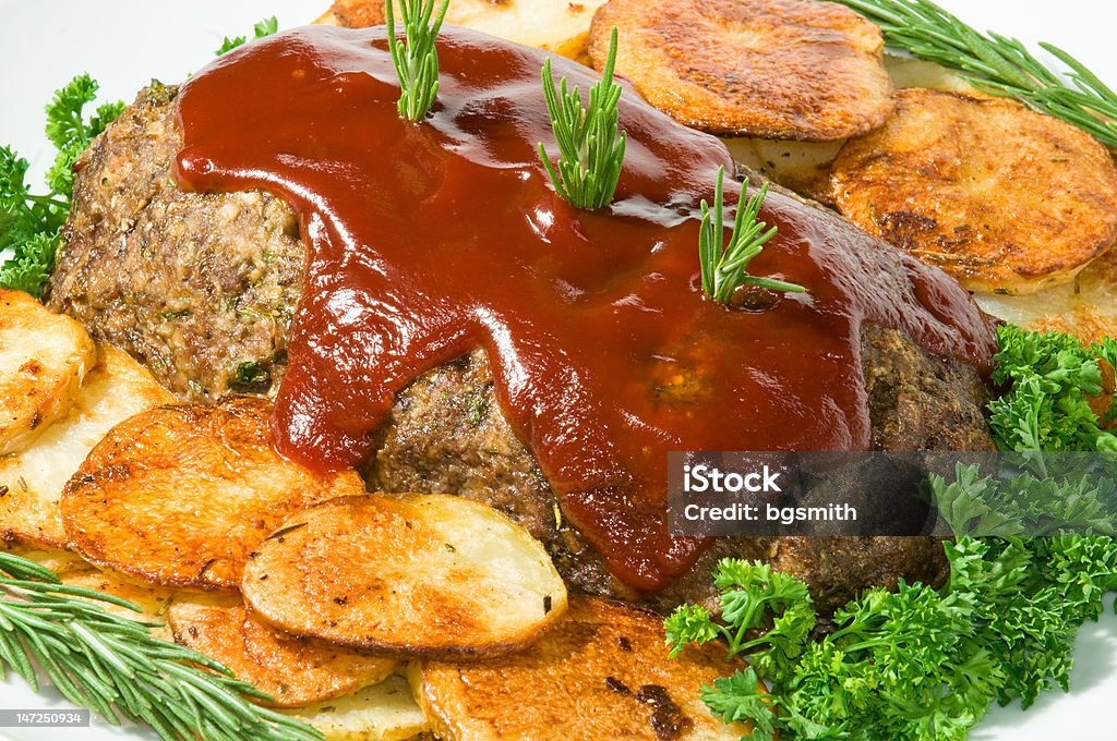 Meatloaf and Potato Dinner Meatloaf with fresh herbs, tomato sauce, and pan fried potatoes on white serving platter. Beef Stock Photo