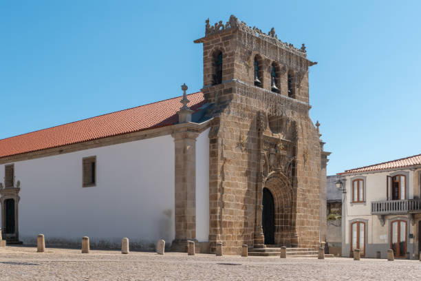 fassade der gotischen manuelinischen kirche aus dem sechzehnten jahrhundert mit einem glockenturm mit drei glocken, pfarrkirche auf dem hauptplatz der stadt vila nova de foz coa, portugal - piazza nova stock-fotos und bilder