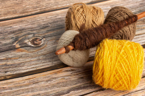 istock Brown and yellow wool spools and a spindle on a wooden background 1472512610