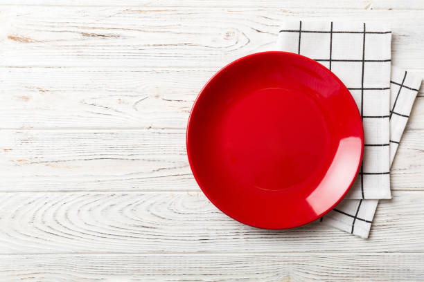 istock Top view on colored background empty round red plate on tablecloth for food. Empty dish on napkin with space for your design 1472513851