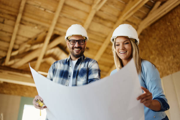 istock Happy couple reading housing plans at construction site. 1472514451