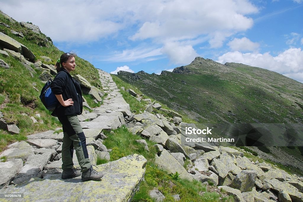 Hiker relaxes in mountains Woman stands on rocky route in mountains and looks on beautiful view Active Lifestyle Stock Photo