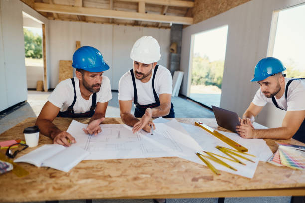 istock Team of workers working on plans and laptop at construction site. 1472515578