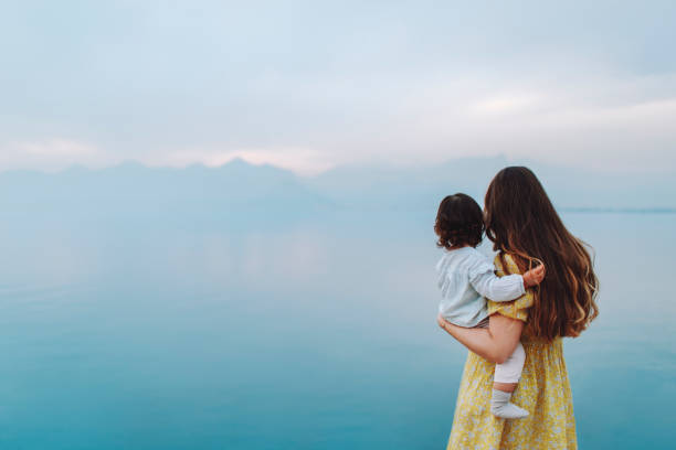 바다를 바라보는 어린 딸과 함께 있는 어머니 스톡 사진