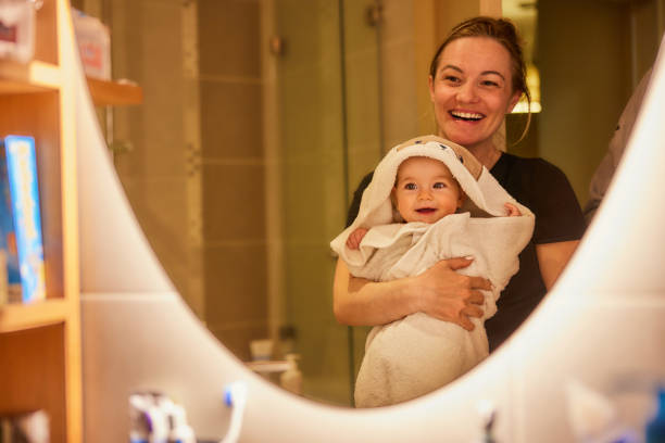 reflexion in einem spiegel von glücklicher mutter und baby mädchen im badezimmer. - mirror mother bathroom daughter stock-fotos und bilder