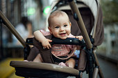 Happy baby girl sitting in stroller outdoors.