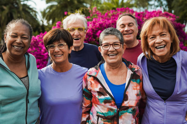 group of senior friends smiling on camera after yoga lesson at city park - aktiva pensionärer bildbanksfoton och bilder