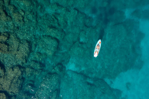 istock Drone view of man lying on a stand up paddle 1472519737