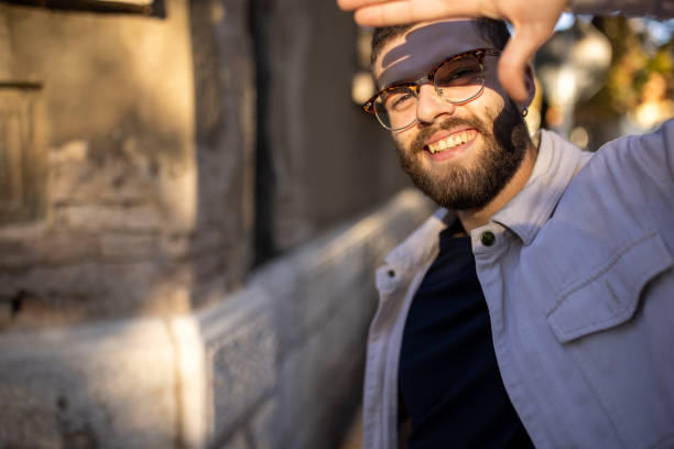 Portrait of young man blocking his face from sunlight