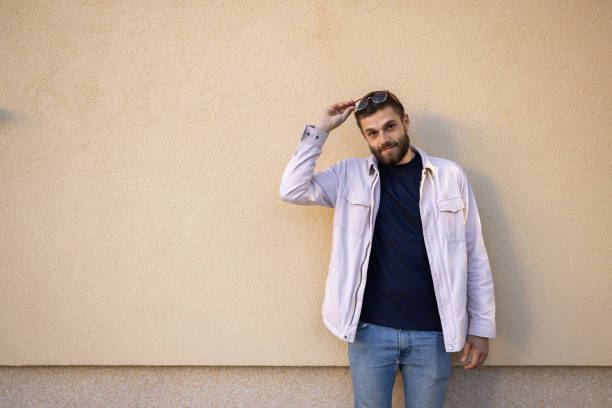 Portrait of a young man leaning against a wall outdoors