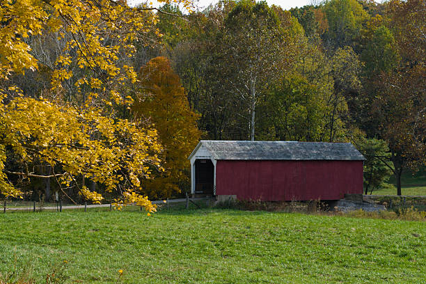 Autumn scene of a covered bridge and colorful surroundings A covered bridge along a country road on an autumn day in Parke County, Indiana. indiana covered bridge stock pictures, royalty-free photos & images