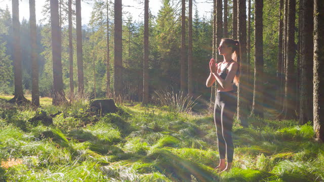 Woman meditates in a serene green forest