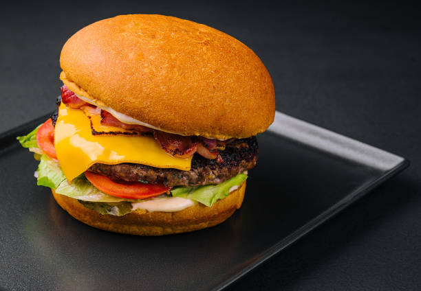 istock Close up tall tasty burger with cheese served on tray 1472528342