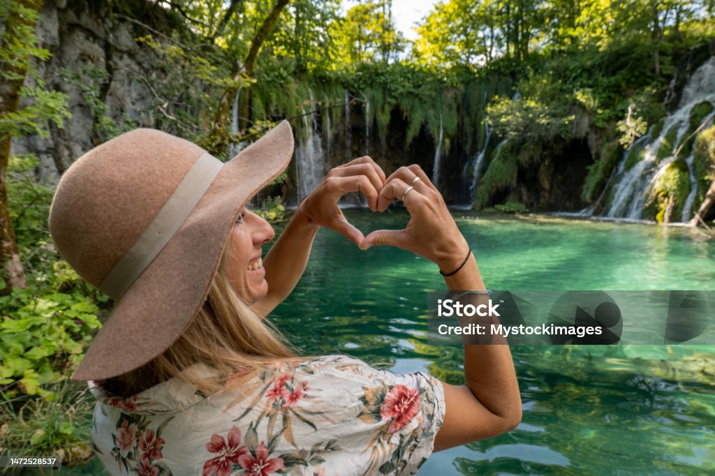 Respect and love to nature, a woman makes a heart frame with her hands to celebrate She makes a heart shape frame with hands on beautiful lake and waterfalls in Croatia. Plitvice Lakes National Park Stock Photo