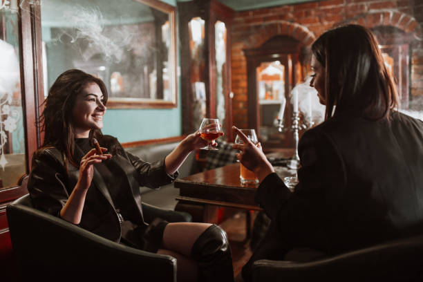 Celebratory Toast With Whiskey And Cigars By Two Beautiful Females stock photo