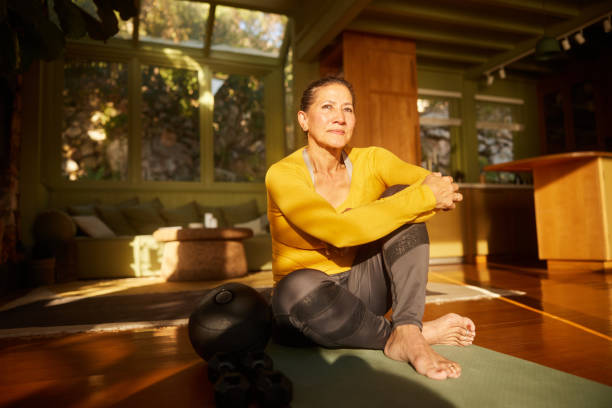 istock Mature woman sitting on an exercise mat after a home workout 1472532130