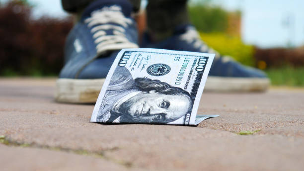Close-up of one hundred dollar bill on the sidewalk and a man who found it stock photo