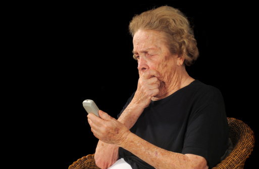 Elderly woman puzzled by an electonic device
