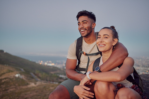 Happy, hiking and mountains with couple and relax for adventure, bonding and travel vacation. Trekking, journey and peace with man and woman sitting in field for fitness, backpacking and happiness