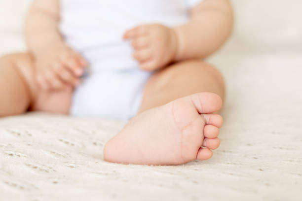 istock baby's legs close up in focus on a white cotton bed 1472536282