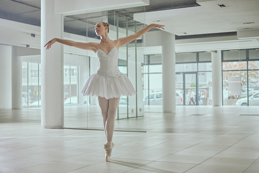 Dance, ballet on toes and ballerina in academy for performance, dancing practice and training. Theatre studio, dancer hobby and woman in elegant pose for creative routine, rehearsal and balance