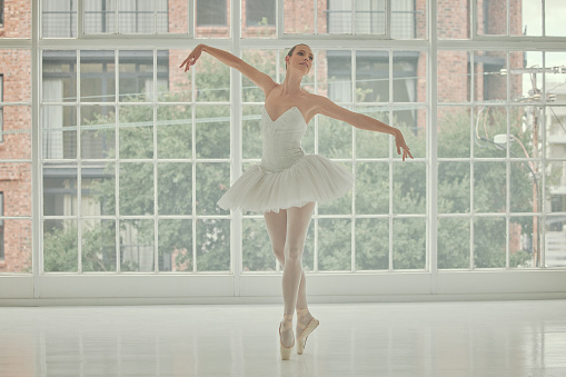 Ballet, woman and dancing on pointe at window for art, music theatre and concert studio. Female ballerina, dancer and learning performance technique, balance and broadway production of body position