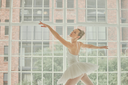 Ballet, woman and dancing at studio window for musical theatre, training and talent class. Female ballerina, dancer and creative freedom of performance, elegant production and broadway artist academy