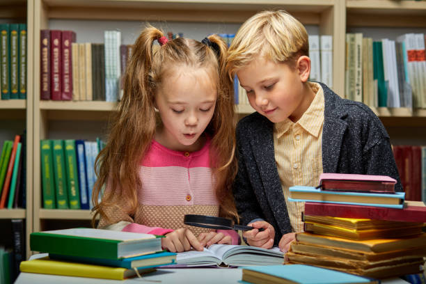 istock school kids reading book together while sitting at table in library 1472538762