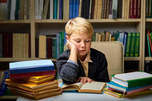 istock sleepy little boy tired of learning doing homework reading book 1472538770