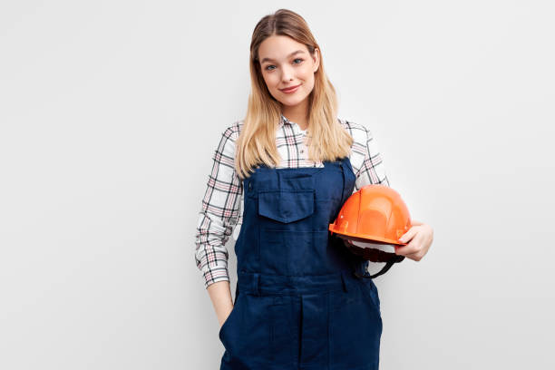 istock Pretty young woman engineer with orange helmet standing with positive expression 1472538872